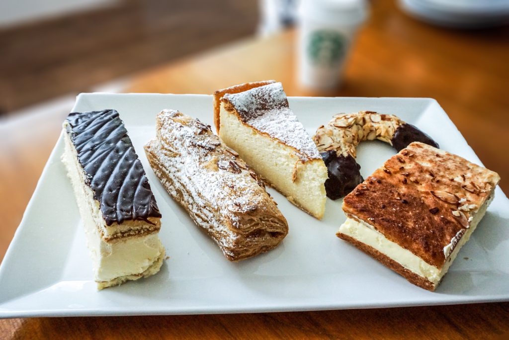 A platter of German desserts and pastries with coffee in a to go cup in background